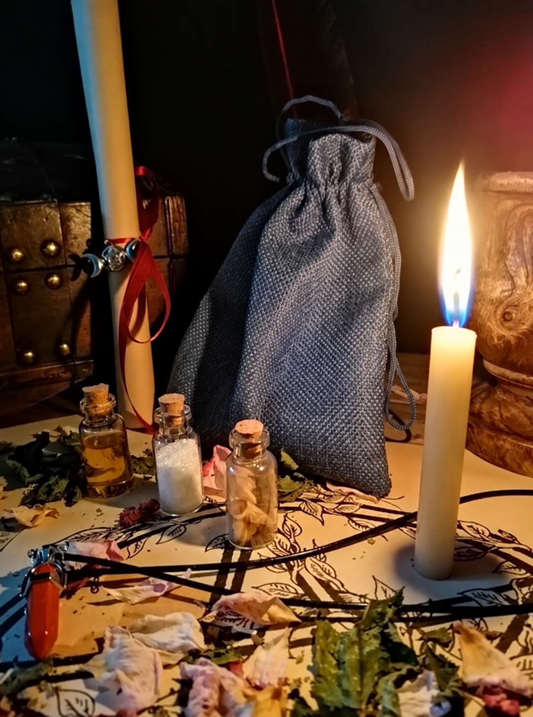 Illustrative scene for Full Moon Spell with a candle, dried plants and small glass vials, adapted from the shared ritual setting.