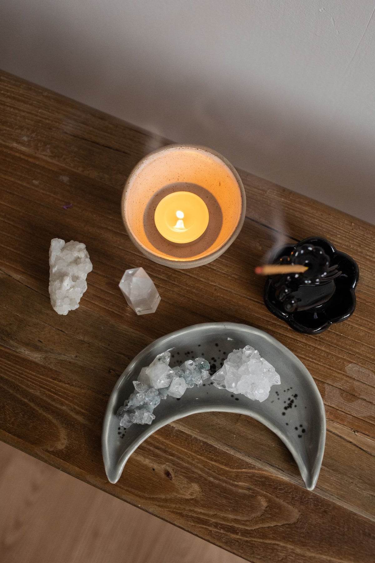Burning candle, incense and a crescent-shaped dish on a wooden table