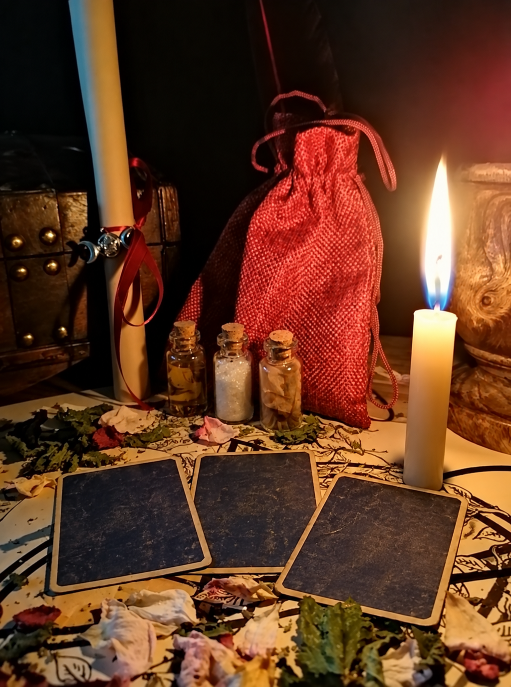 Illustrative tarot arrangement with face-down cards, an ivory candle and small glass vials. This is not an individual customer's reading.