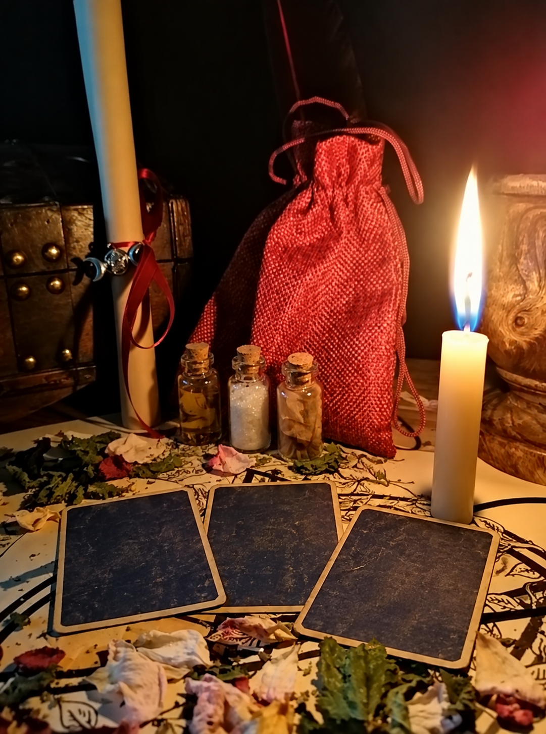 Illustrative tarot arrangement with face-down cards, an ivory candle and small glass vials. This is not an individual customer's reading.